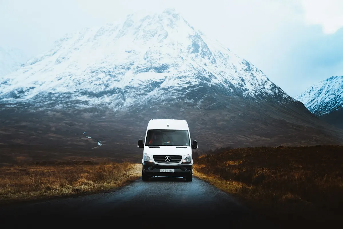 A white van driving along a highland road.